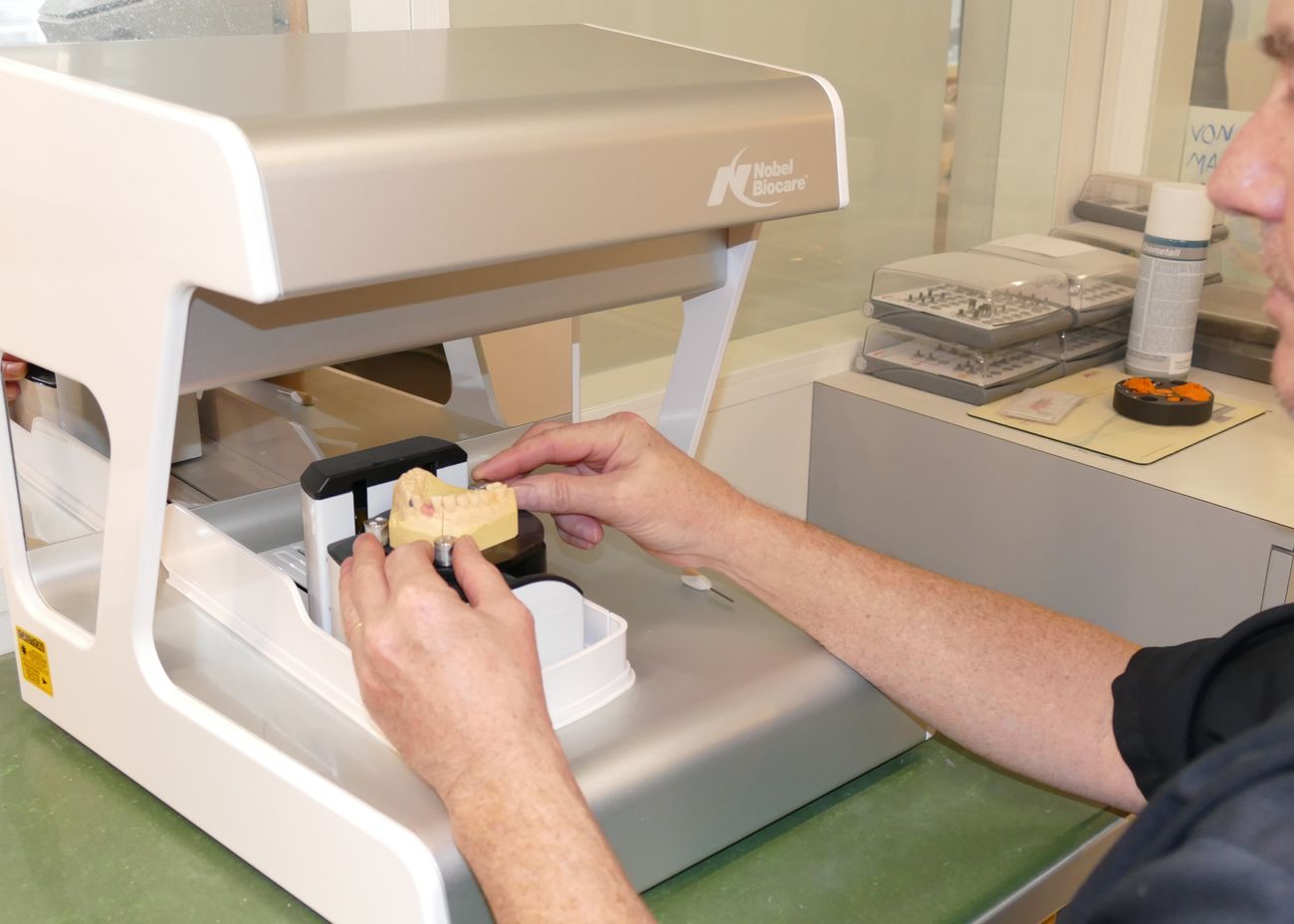 Zahntechniker legt ein Gipsmodell in den Laborscanner ein